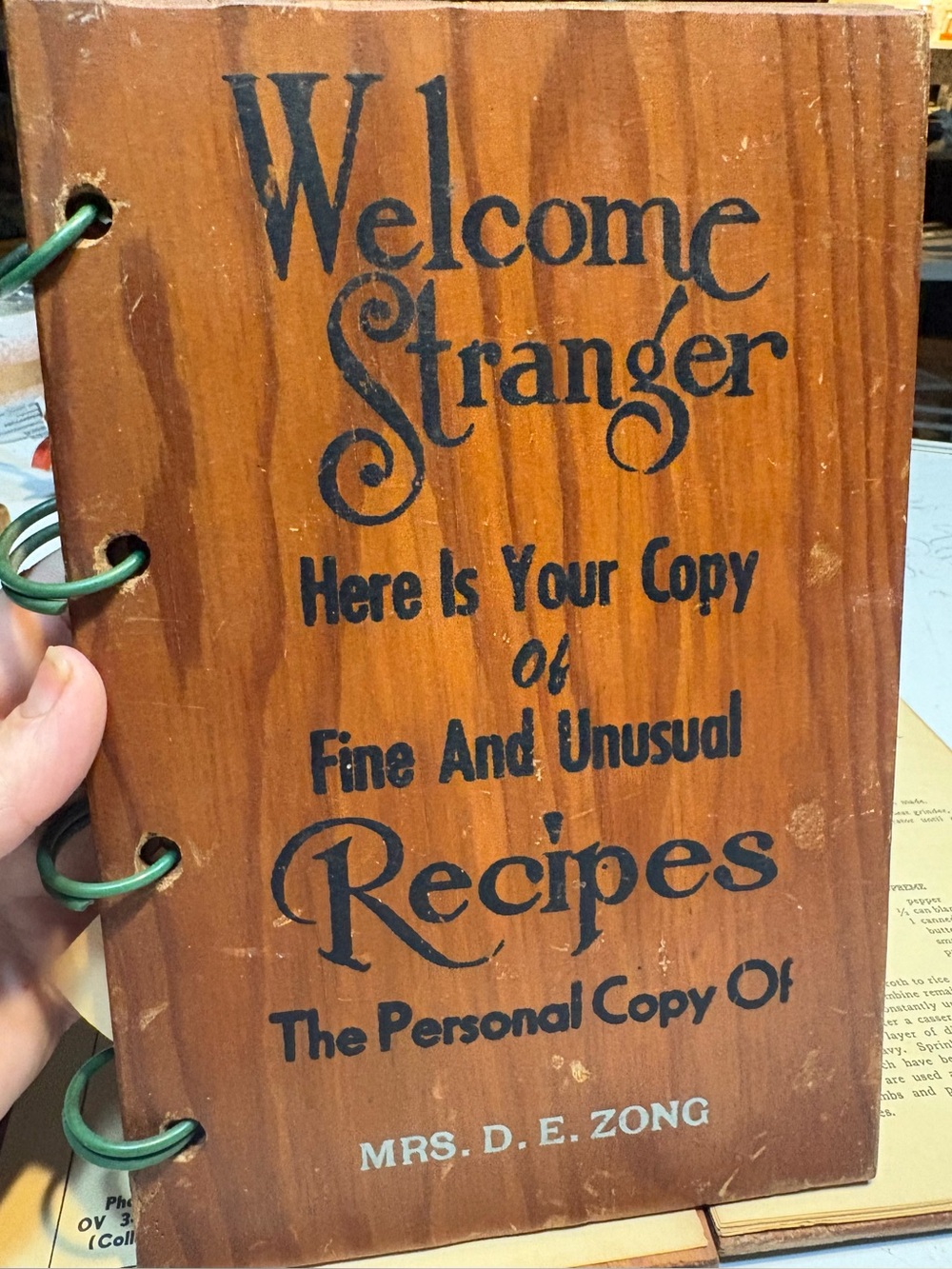 wooden-cover cookbook titled "Welcome Stranger Here Is Your Copy of Fine recipes